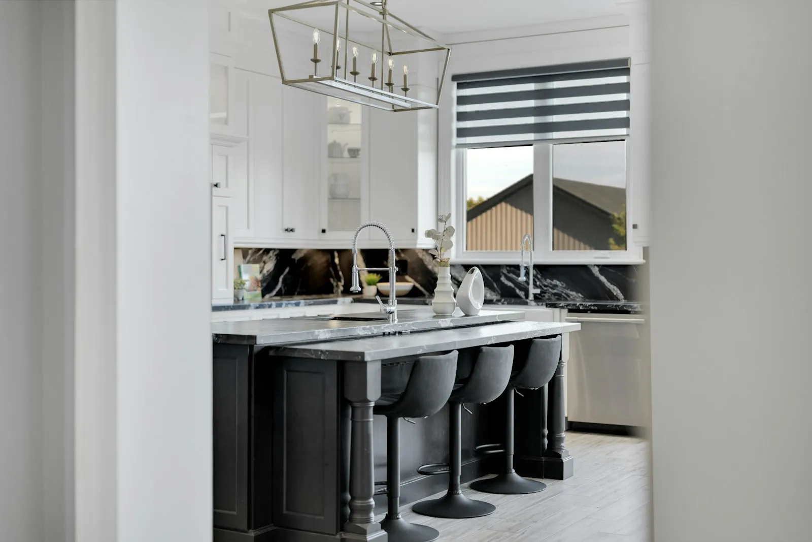Dapur island modern dengan kabinet putih dan kayu, meja marmer, dan kursi bar kayu